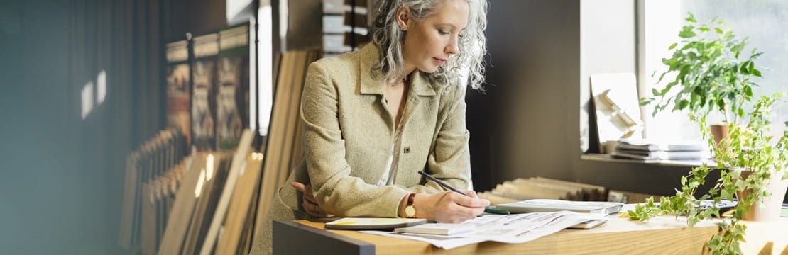 Business owner reviewing plans at a desk, demonstrating sustainable decision-making that can reduce costs and strengthen long-term growth.