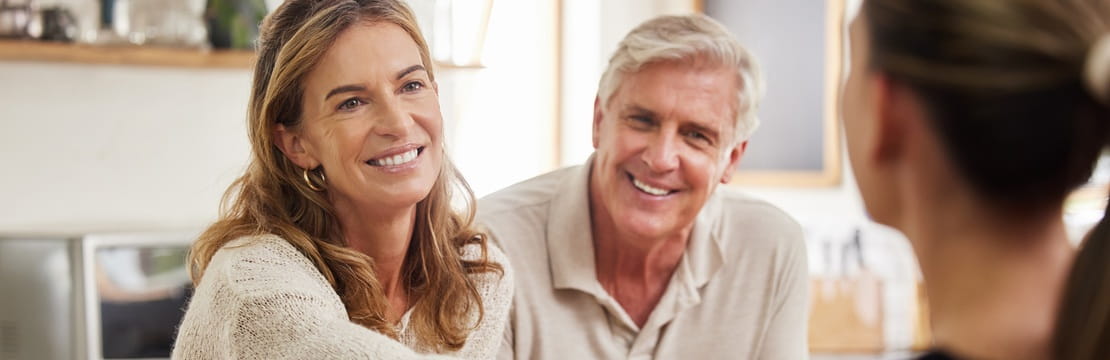 Smiling couple meeting with a financial advisor to discuss secure retirement planning through a trusteed IRA.