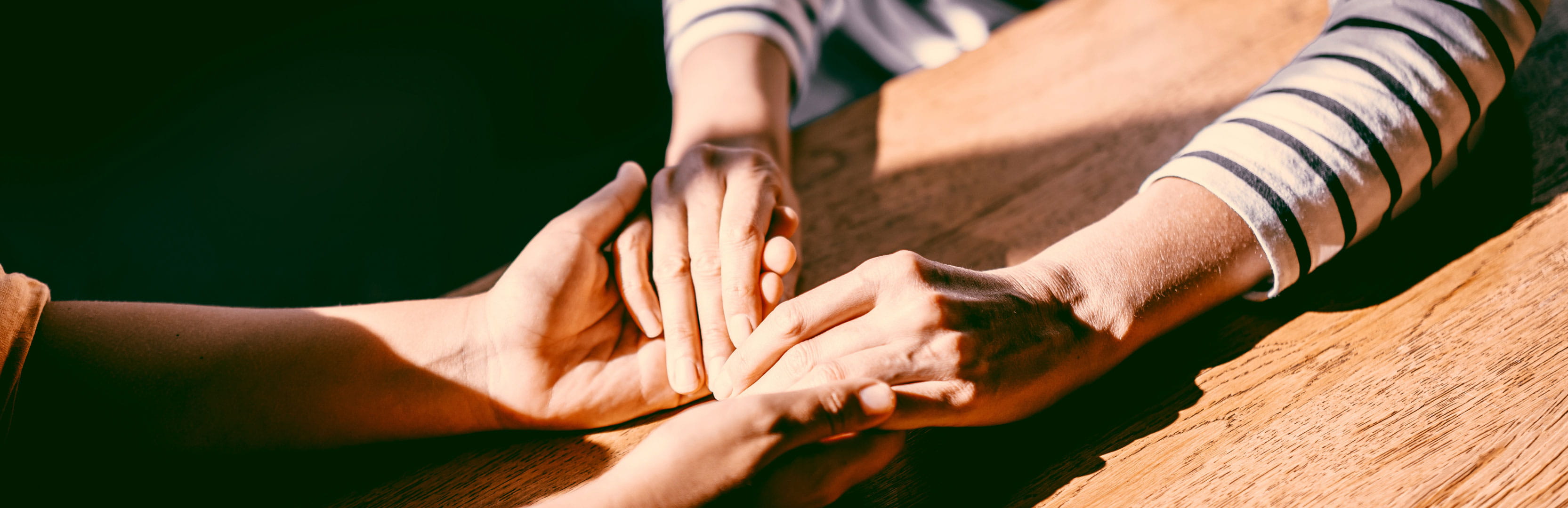 Two people hold hands across a table, symbolizing how estate planning can strengthen family connections, build generational wealth, and reflect personal values and legacy.